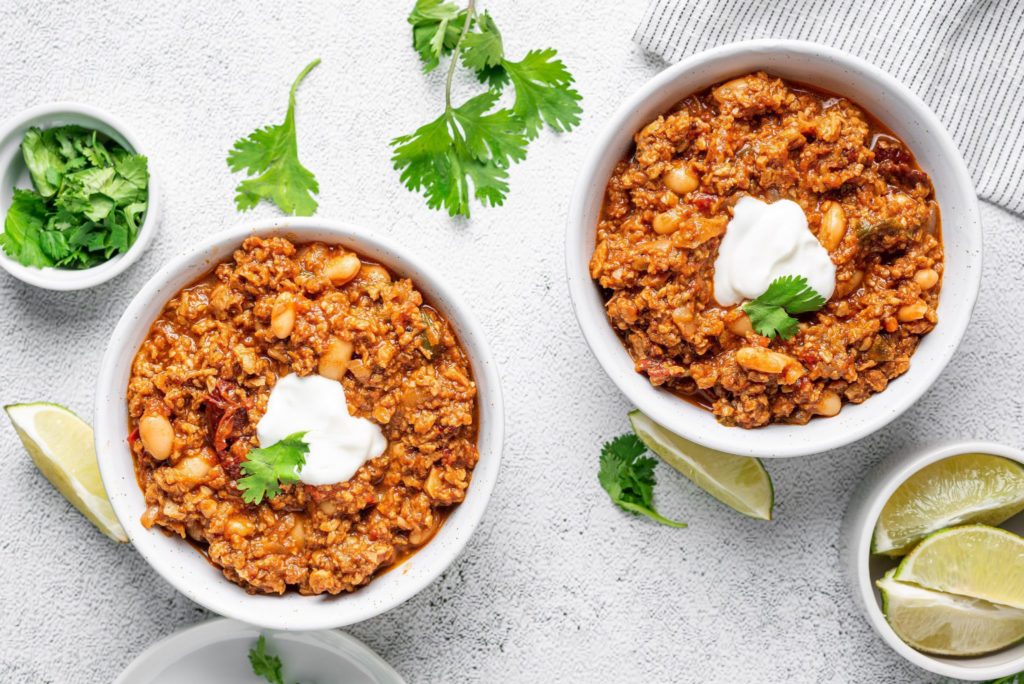 Two bowls of Hungry Planet beef chili topped with sour cream and cilantro