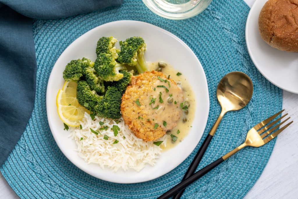 Hungry Planet chicken piccata on a plate with broccoli, rice, and lemon slices