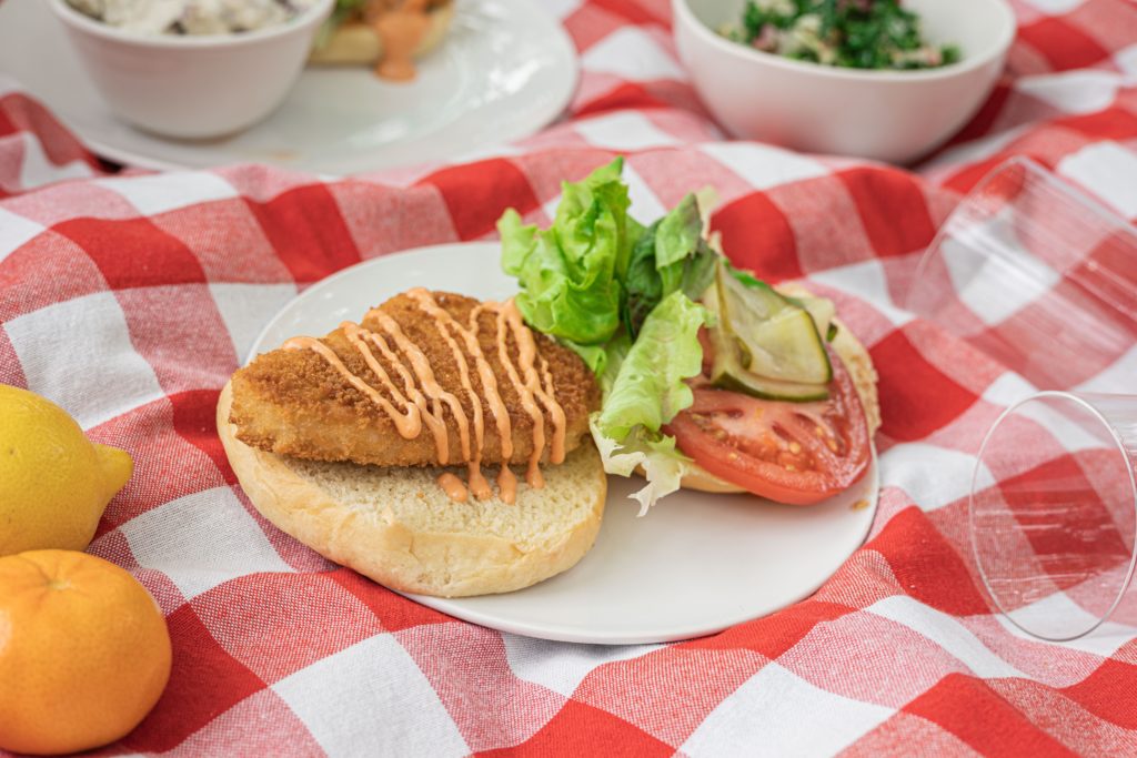 Hungry Planet crispy fried chicken sandwich with chipotle mayo and toppings on a picnic blanket